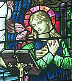 Detail from stained glass window by Henry Holiday showing figure reading from a lectern
