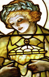 Stained glass angel holding lamp with the word Peace illuminated