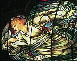 Stained glass representation of angel carrying a scroll with Blessed are the Peacemakers from the Beatitudes